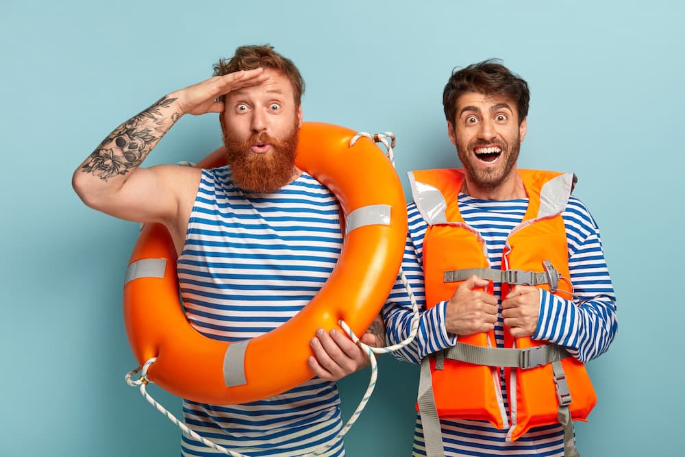 cheerful-guys-posing-beach-with-lifejacket-lifebuoy-1